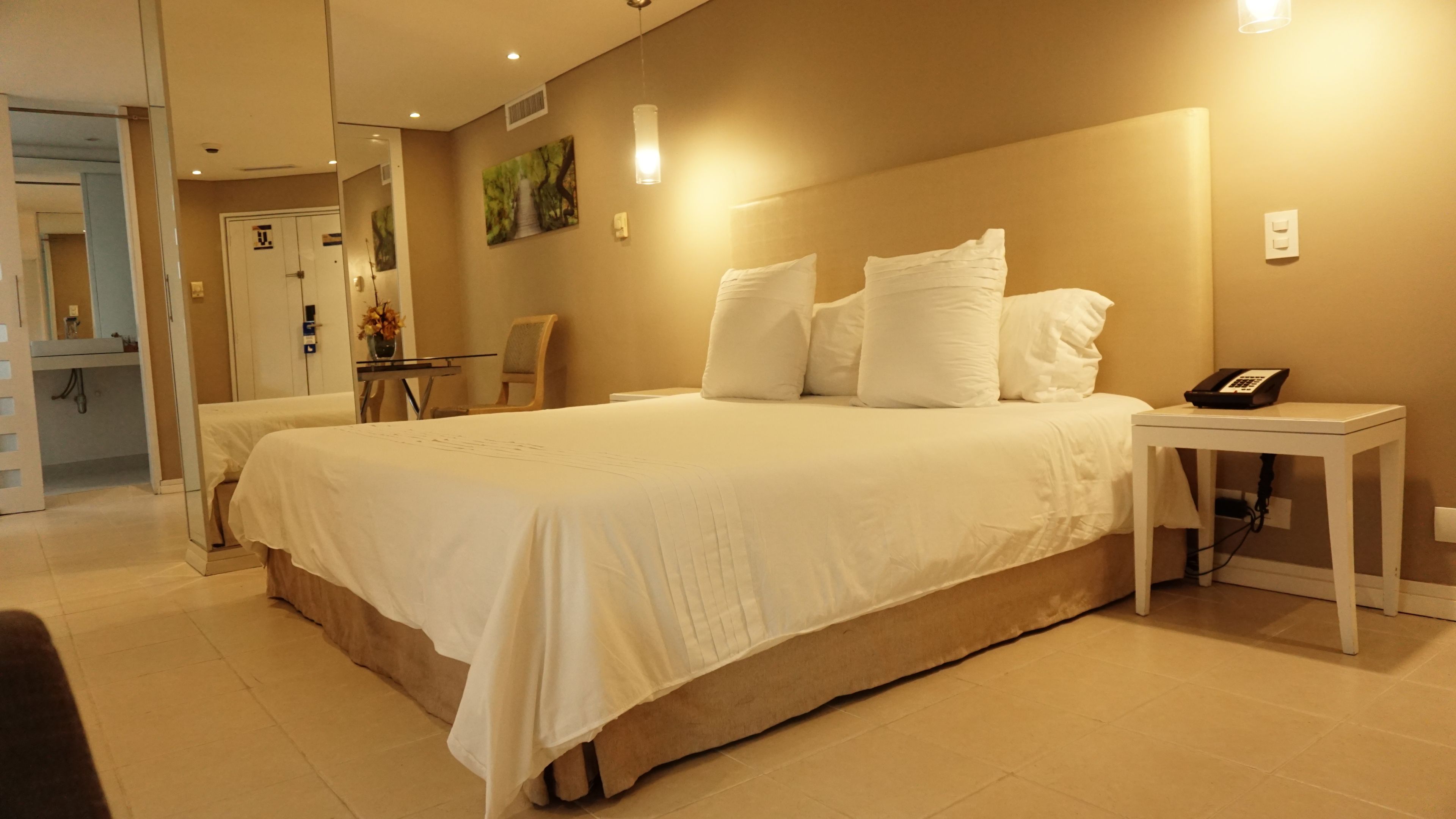 A hotel room with a large bed, bedside table, and a phone.