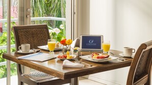 A breakfast table with plates of food, a laptop, and a cup of coffee.