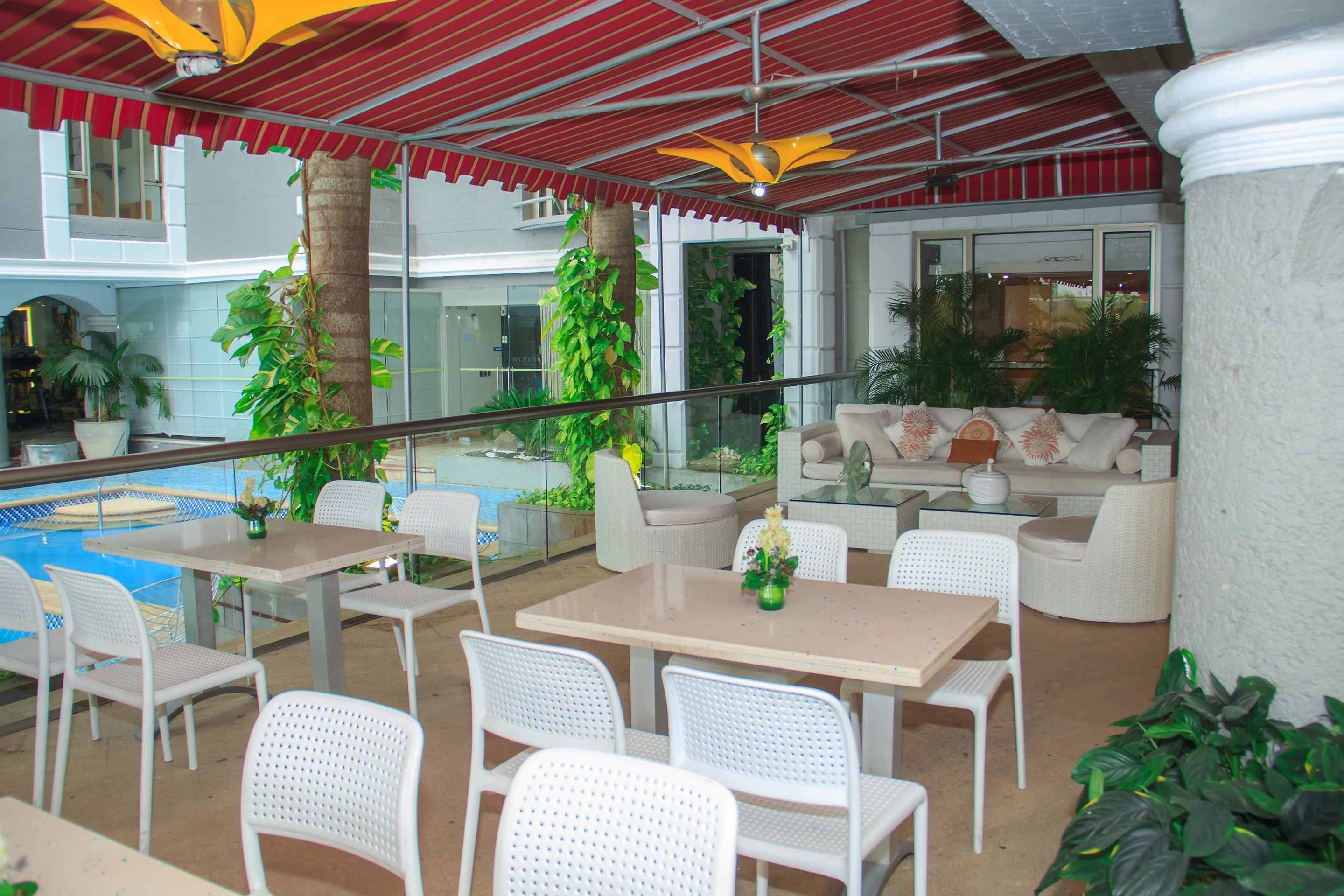 An indoor patio area with tables and chairs, a pool, and various plants.