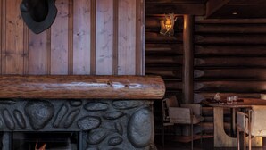 Un interior rústico con chimenea de piedra, paneles de madera y un venado montado en la pared.