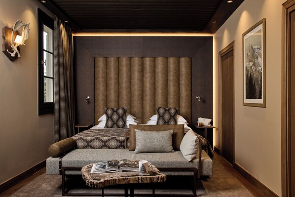 A modern bedroom with a large bed, a bedside table, and a reading area with a book and mug.