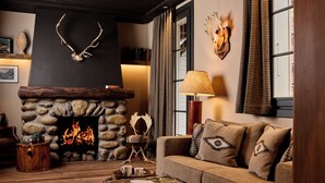 Un salón acogedor con una chimenea de piedra, un sofá con cojines estampados y una mesa de centro con un libro.