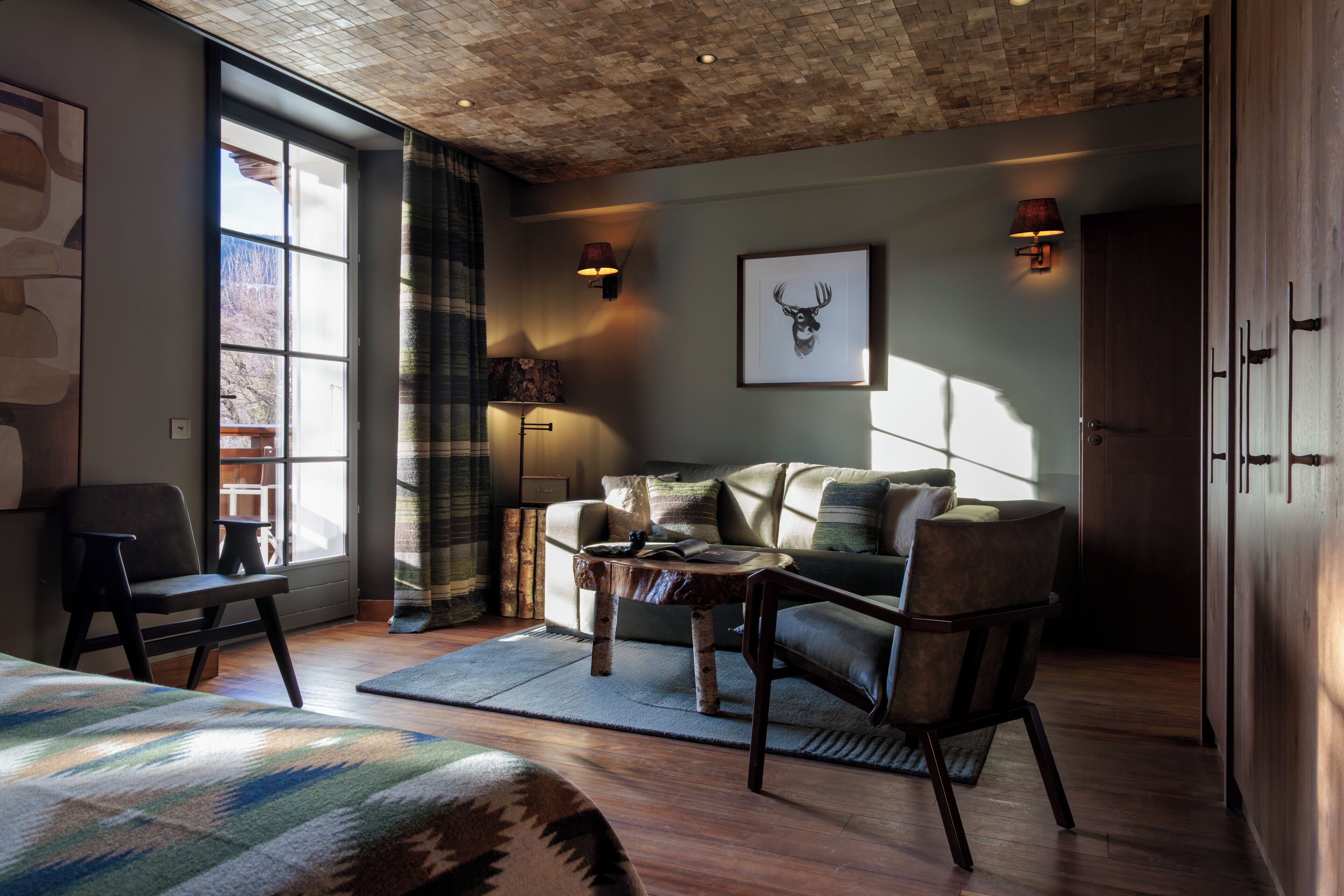 A cozy room with a large window, a sofa, a coffee table, and a bed.