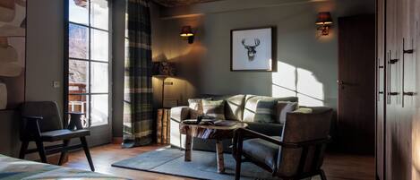 A cozy room with a large window, a sofa, a coffee table, and a bed.