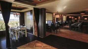 A spacious dining area with a large table and chairs, a chandelier, and a view of the outdoors.