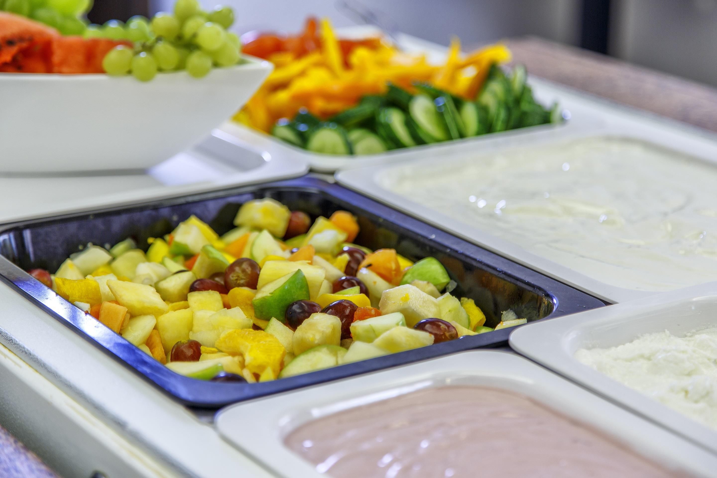 Un buffet proposant une variété de plats, notamment des fruits, des légumes et des sauces pour tremper.