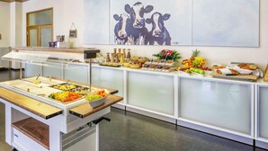 Dispositiu de buffet amb diversos plats i un quadre de vaques a la paret.