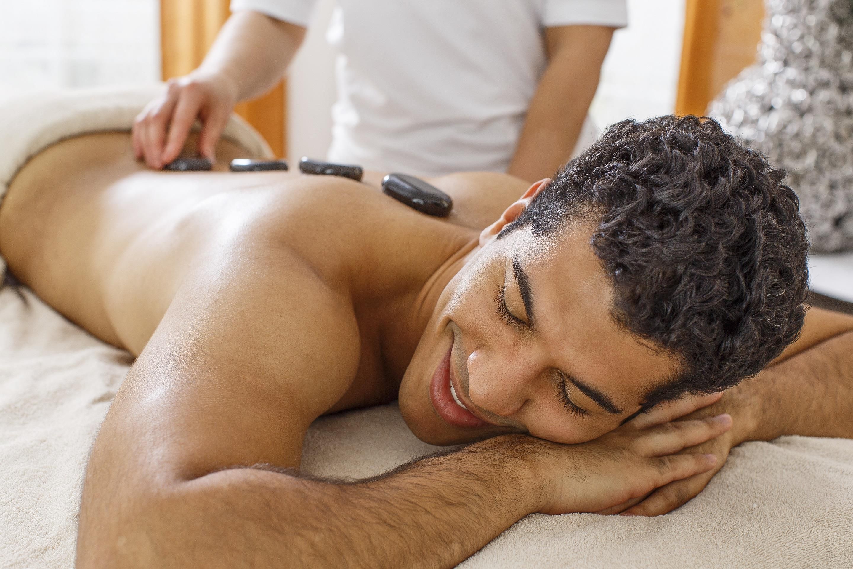 A person lying on a massage table receiving a back treatment.