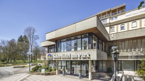 Un hotel amb un disseny modern, amb grans finestres de vidre i un cartell que diu "Soleo Hotel am Park".