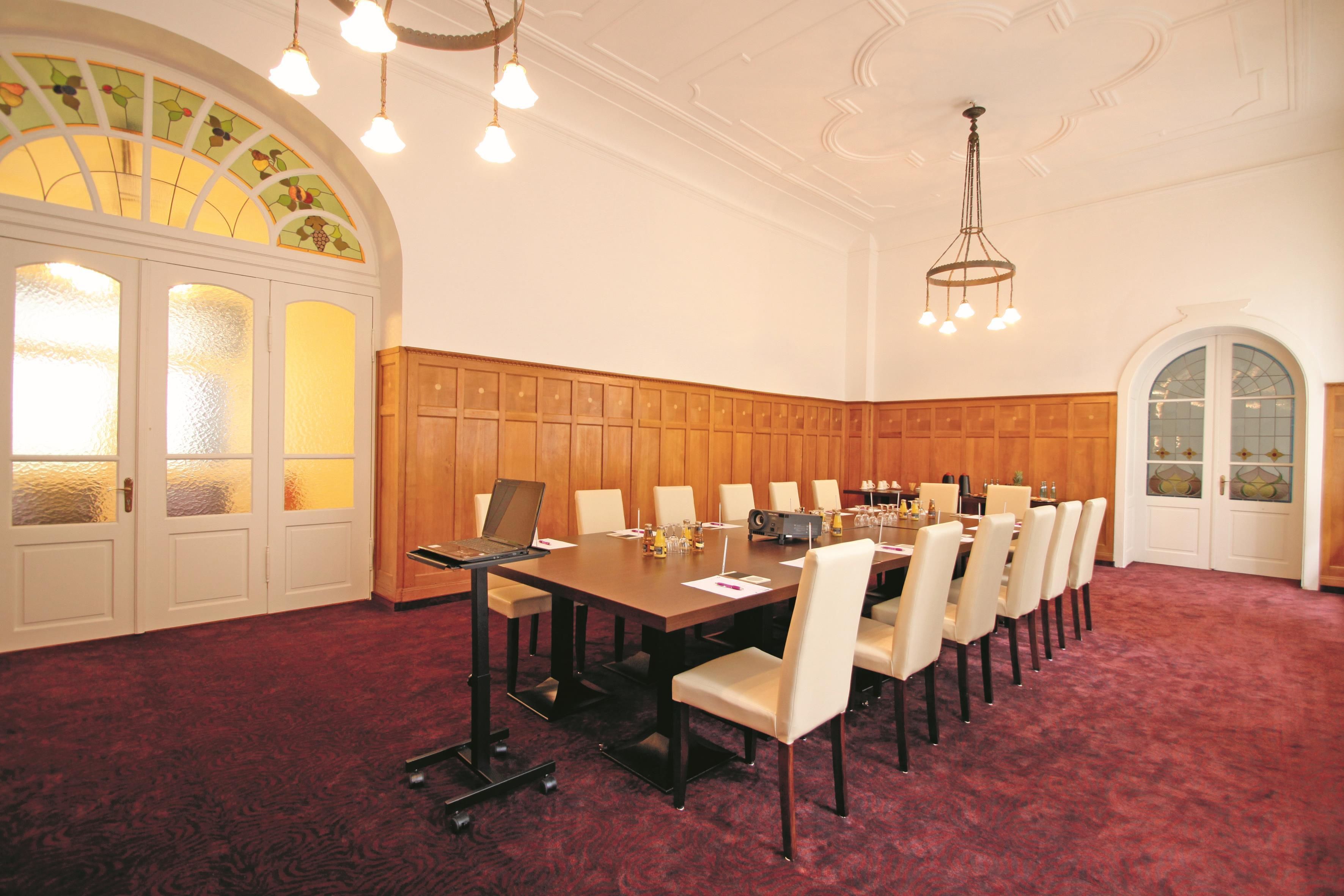 A conference room with a long table, chairs, a laptop, and a projector.