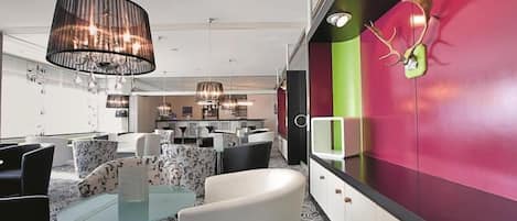 Un interior moderno con una zona de comedor, una cocina al fondo y una pared vibrante con un adorno de asta de ciervo.