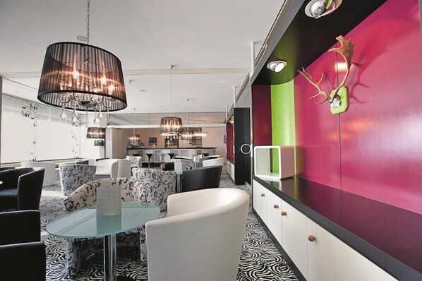 Een modern interieur met een eethoek, een keuken op de achtergrond, en een levendige wand met een decoratief gewei.