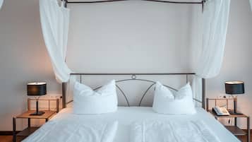Ein Doppelbett mit weißen Laken, ein Metall-Kopfstück, zwei Nachttische mit Lampen und eine Steckdose an der Wand.