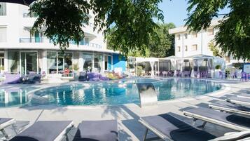 Alberca al aire libre, sombrillas en la alberca y camastros