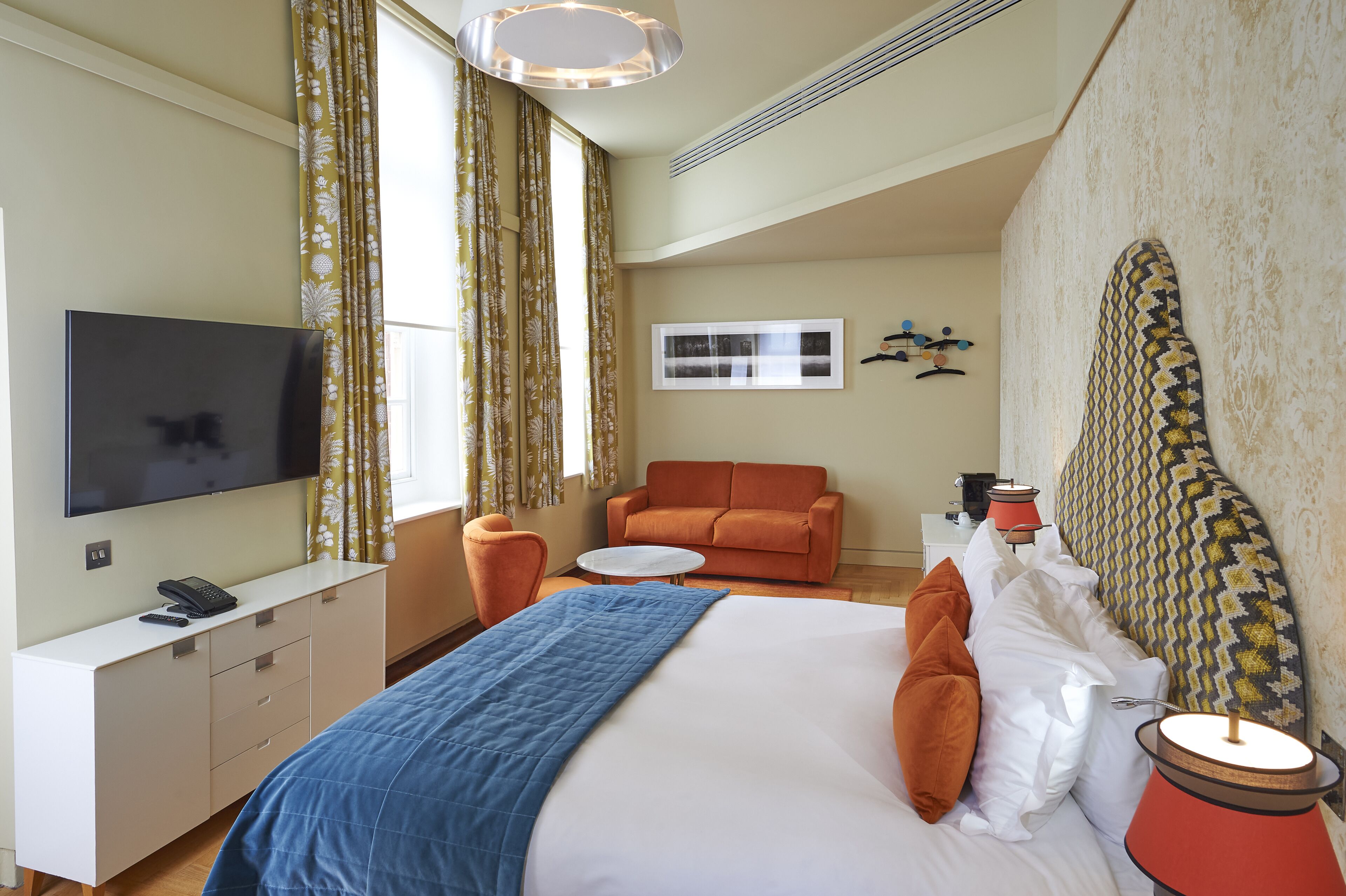 Une chambre d’hôtel équipée d’un lit, d’une télévision, d’un bureau, d’une chaise et d’un canapé.