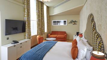 A hotel room with a bed, a TV, a desk, a chair, and a sofa.