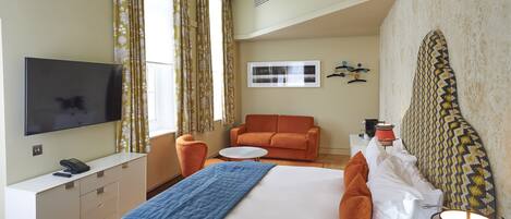 Une chambre d’hôtel équipée d’un lit, d’une télévision, d’un bureau, d’une chaise et d’un canapé.