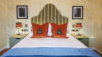 A neatly made bed with a patterned headboard, two nightstands with lamps, and framed pictures on the walls.