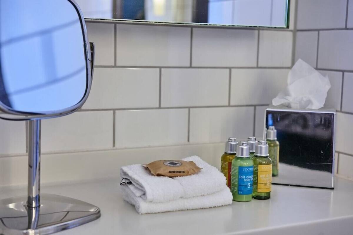 A bathroom with a mirror, a towel, and toiletries on the counter.