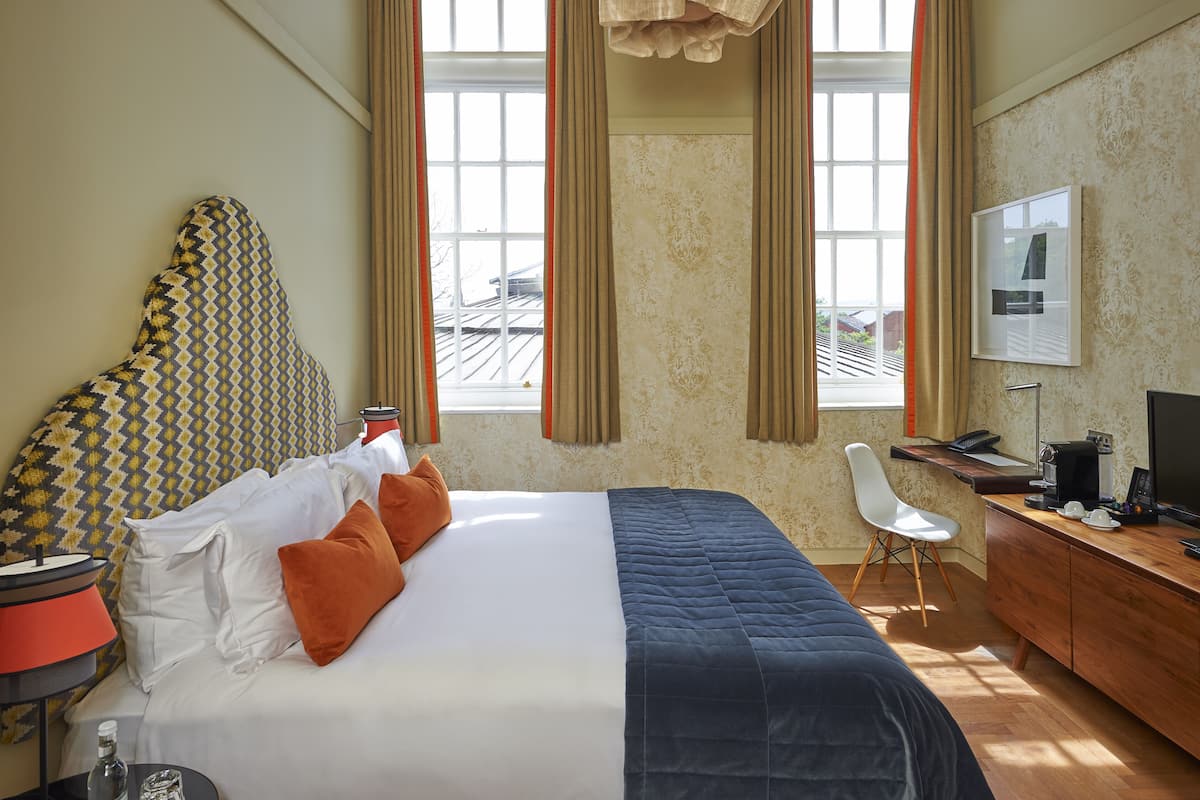 A hotel room with a bed, a desk, a chair, and a TV.