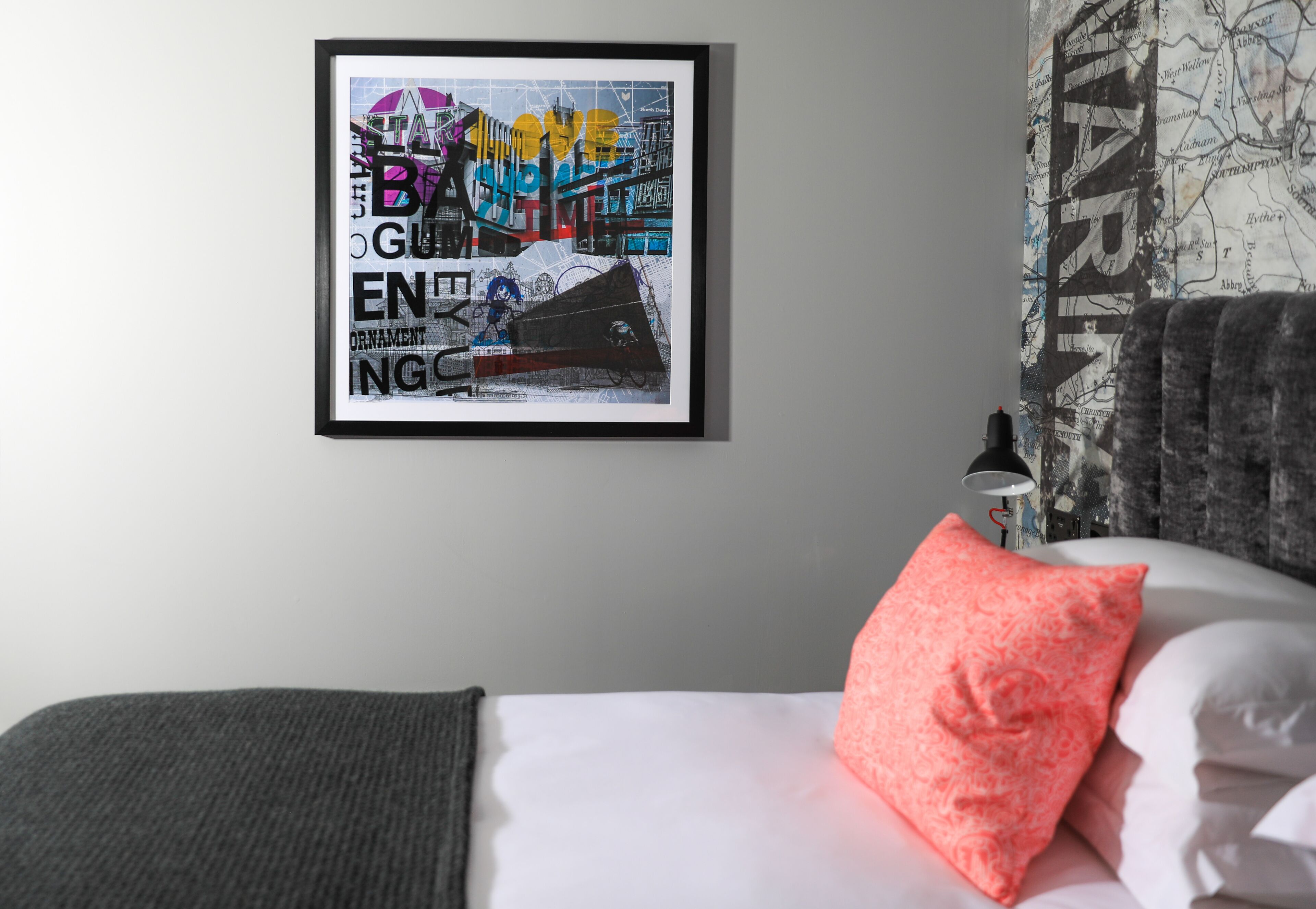 Ein Schlafzimmer mit einem Bett, einem gerahmten Kunstwerk an der Wand und einer Lampe auf einem Nachttisch.