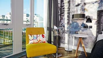 A modern room with a yellow chair, a round table, a floor lamp, and a wall with a map design.