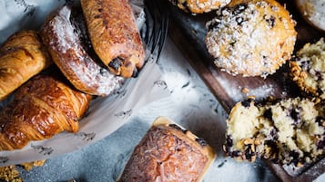 Une variété de produits de boulangerie, notamment des pâtisseries et des muffins, disposés sur une planche en bois et du papier.