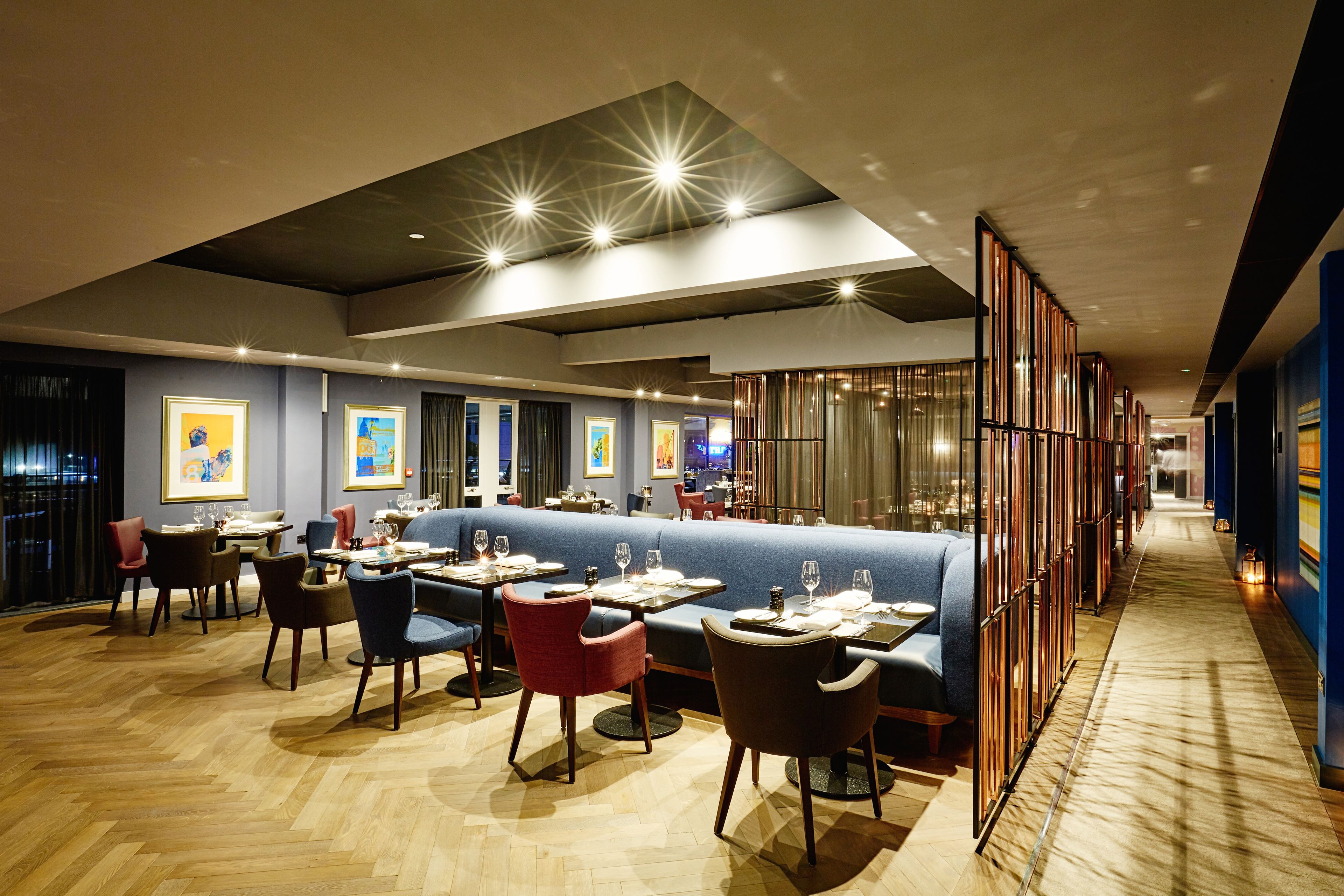 A modern restaurant with a long counter, booths, and a variety of seating options.