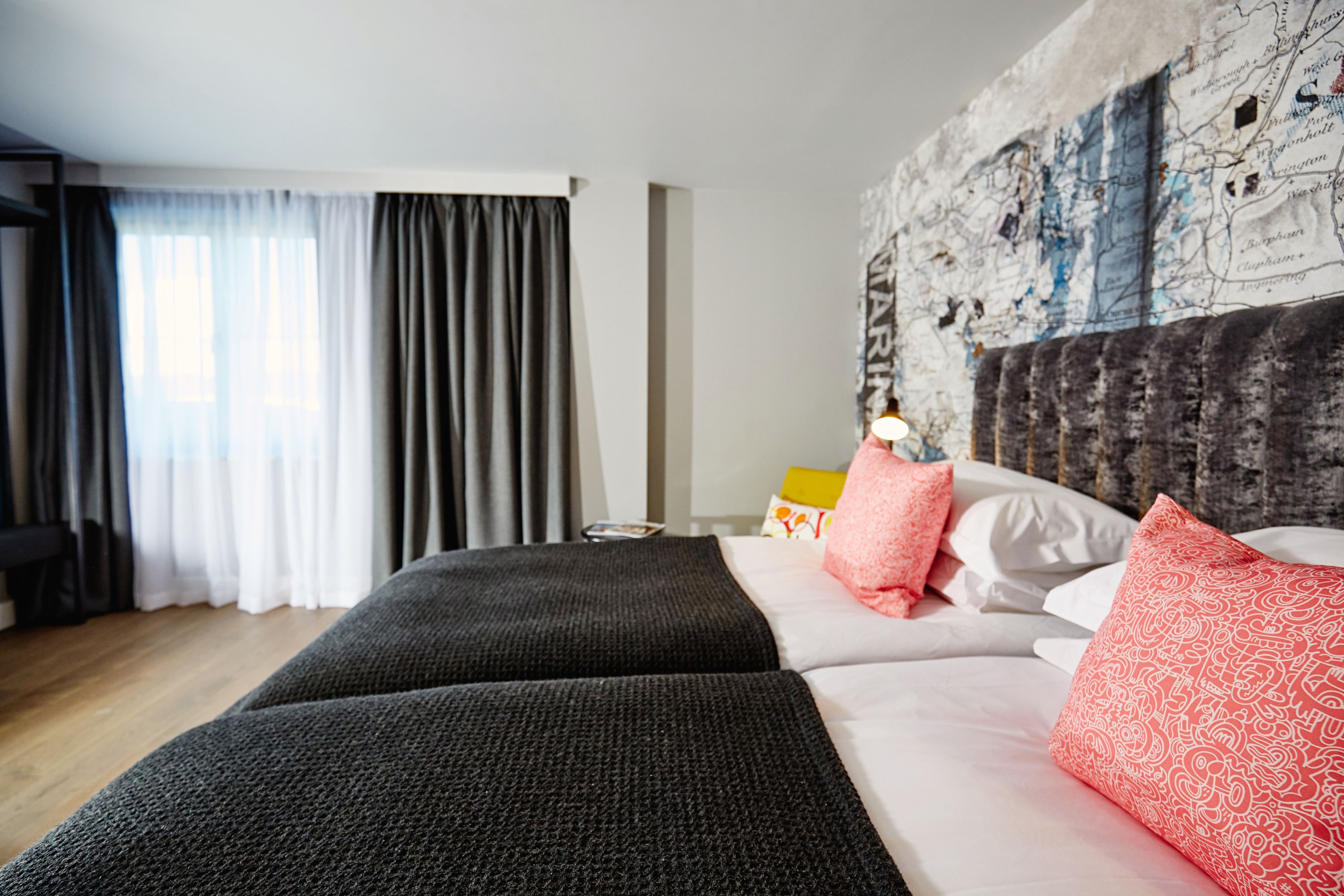 Una habitación de hotel con una cama grande, un mapa en la pared y vistas de la ciudad a través de la ventana.