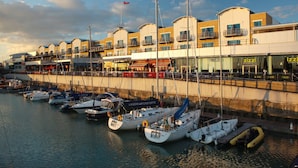 A marina with several boats docked, a waterfront building with shops, and a clear sky. - Malmaison Brighton (Brighton)