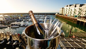 A champagne bottle in a metal bucket with glasses, overlooking a marina with boats and buildings. - Malmaison Brighton (Brighton)