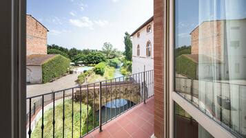 A balcony with a view of a courtyard, a bridge, and a river.