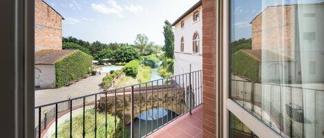 A balcony with a view of a courtyard, a bridge, and a river.