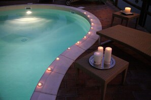 Una piscina al aire libre, sombrillas, sillones reclinables de piscina
