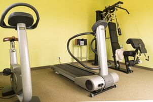 Un gimnasio con cinta de correr, bicicleta estática y máquinas de pesas.