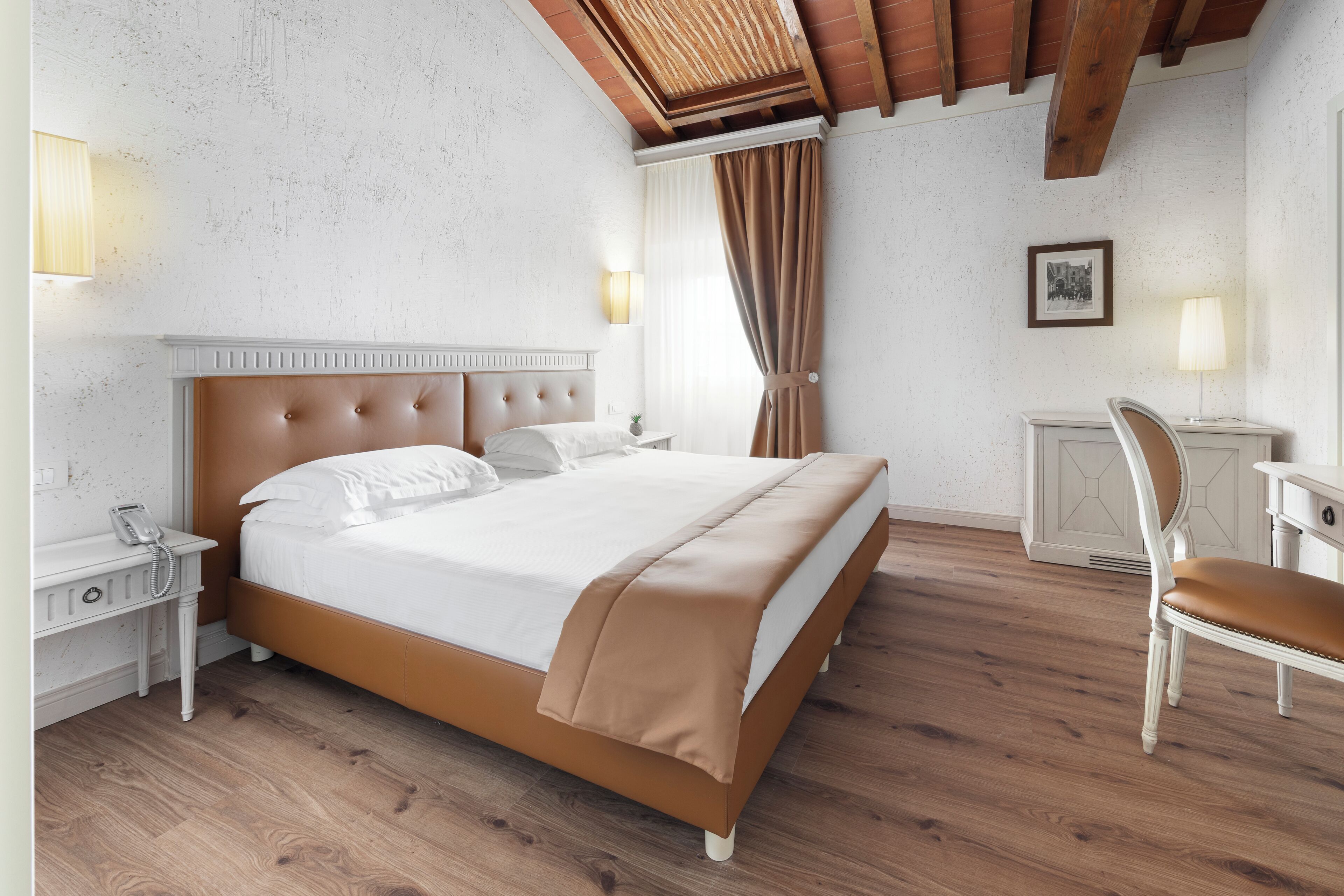 A bedroom with a bed, bedside tables, a chair, a desk, and a lamp.