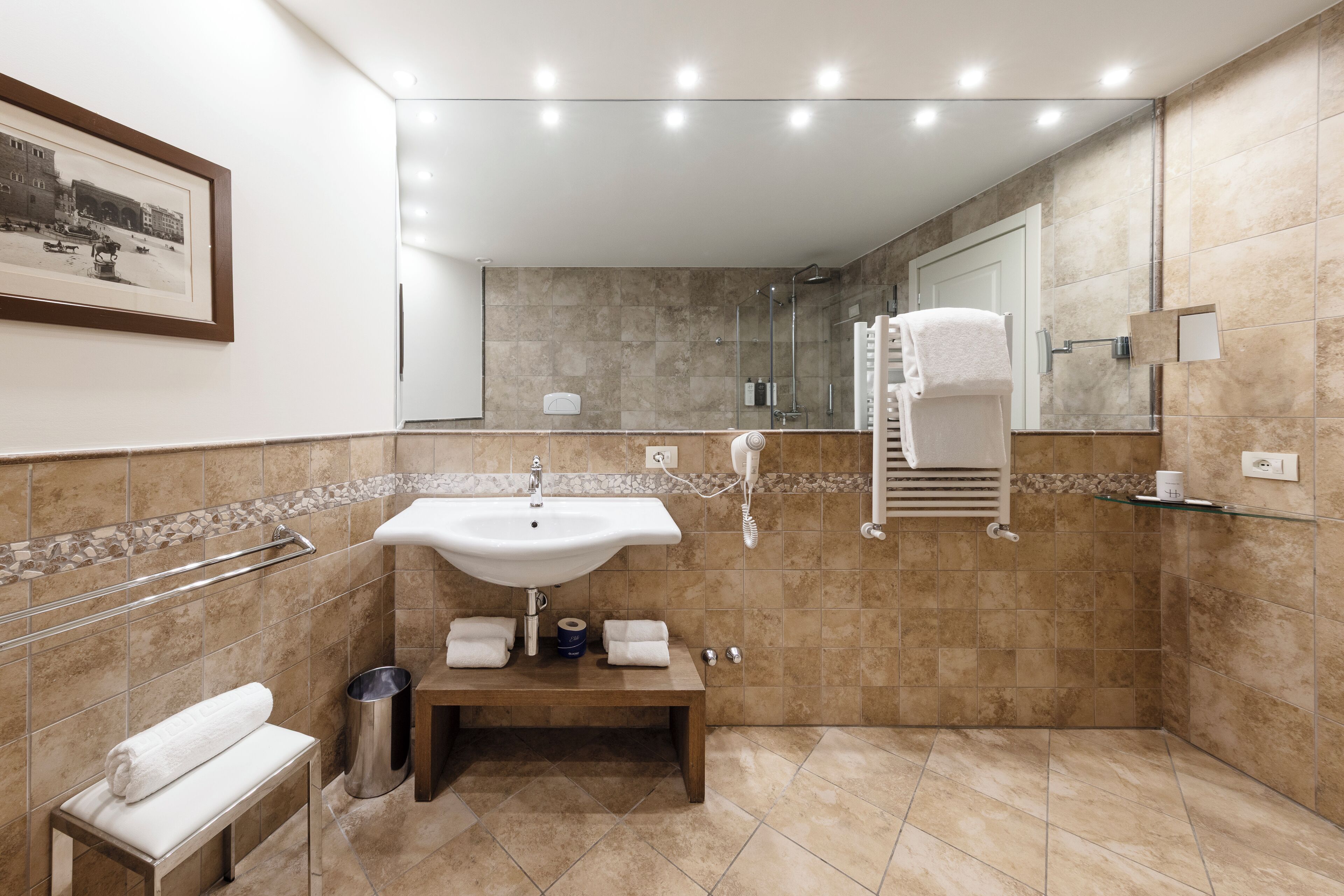 A modern bathroom with a sink, mirror, and shower.