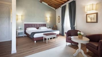 Une chambre à coucher avec un grand lit, des tables de chevet, une chaise et une petite table sur laquelle est posé un vase.