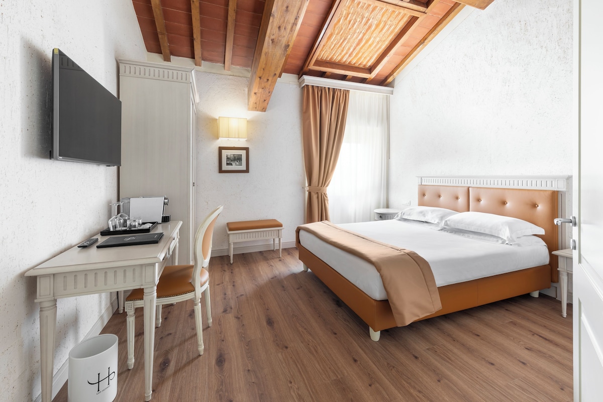A bedroom with a bed, a desk, a chair, a lamp, and a window with curtains.