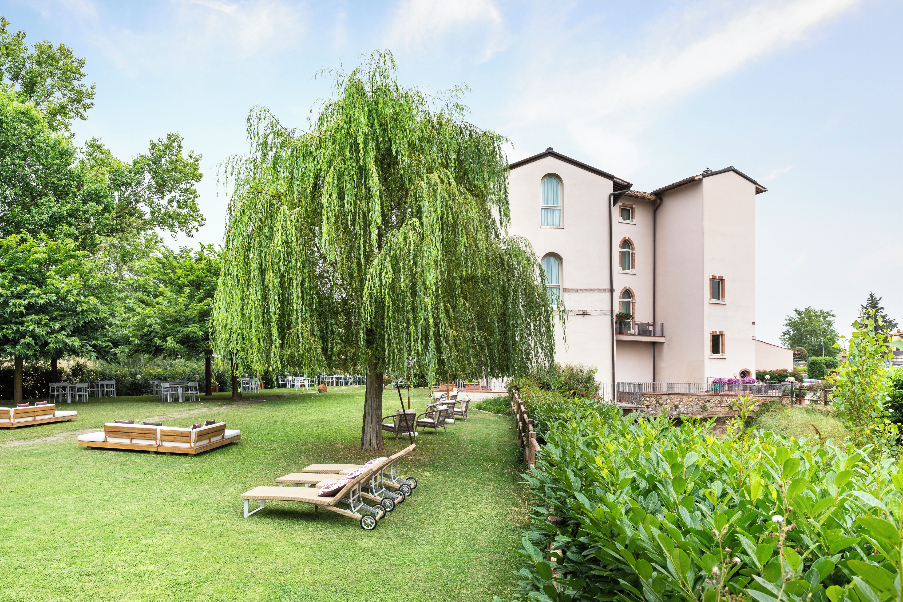 A garden with seating, a large tree, and a building with balconies.