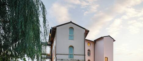 A two-story building with a balcony, a small bridge, and a stream in front.