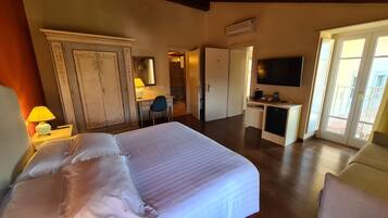 Una habitación de hotel con una cama grande, un escritorio, una silla, un televisor y un armario.