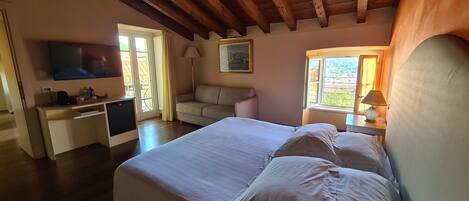 A bedroom with a bed, a desk, a television, and a window with curtains.