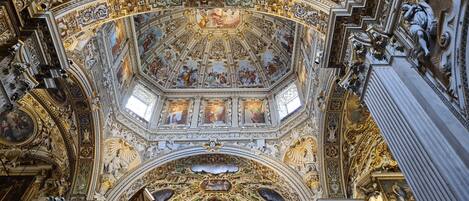 A highly ornate ceiling with intricate frescoes and gold accents.