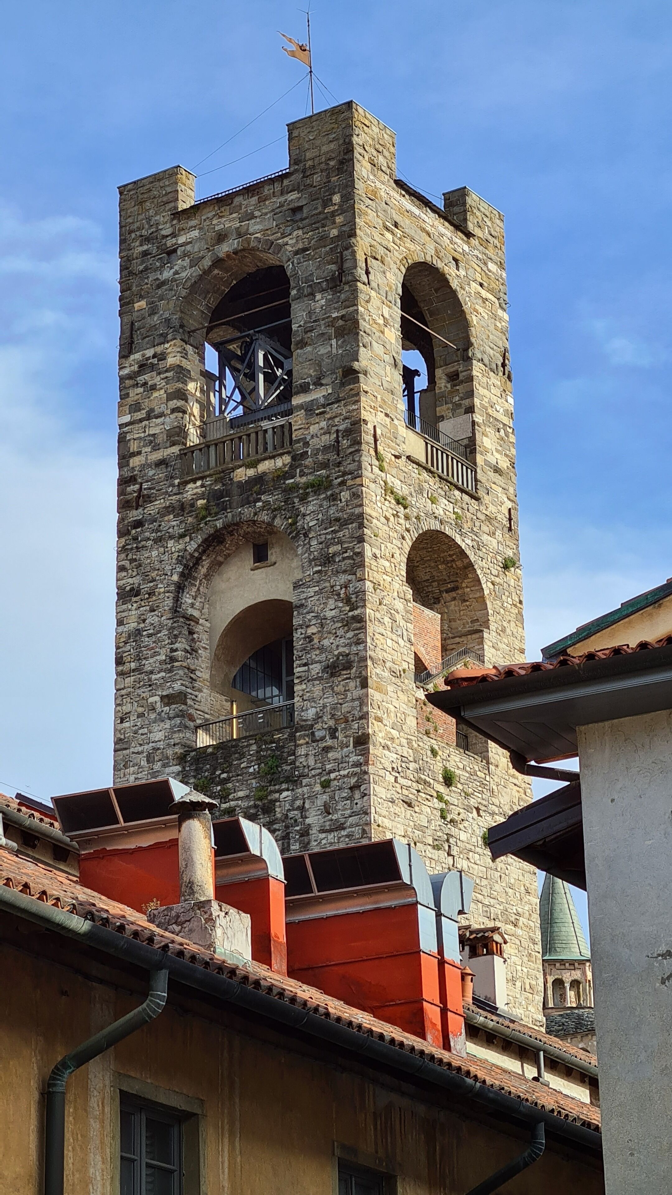 A stone bell tower with arched openings and a weather vane on top.