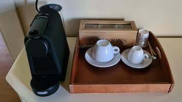 Una máquina de espresso DeLonghi, dos tazas blancas y una bandeja con una caja etiquetada 'INNSIONS'.