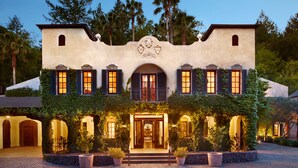 A large, stucco building with a central entrance, surrounded by lush greenery and potted plants. - Kenwood Inn and Spa (Kenwood)