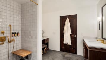 A modern bathroom with a shower, vanity, and a wooden bench.