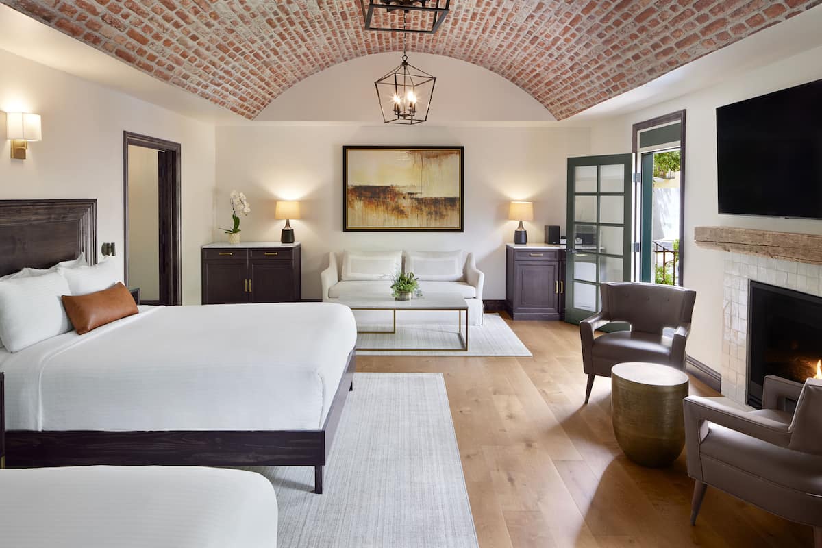 A spacious bedroom with a large bed, a sofa, and a fireplace.