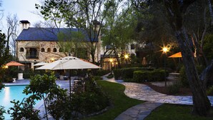A stone pathway leading to a pool area with outdoor seating and umbrellas. - Kenwood Inn and Spa (Kenwood)